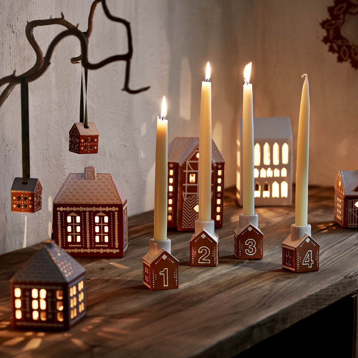 Tända adventsljus i små ljusstakar som ser ut som pepparkakshus