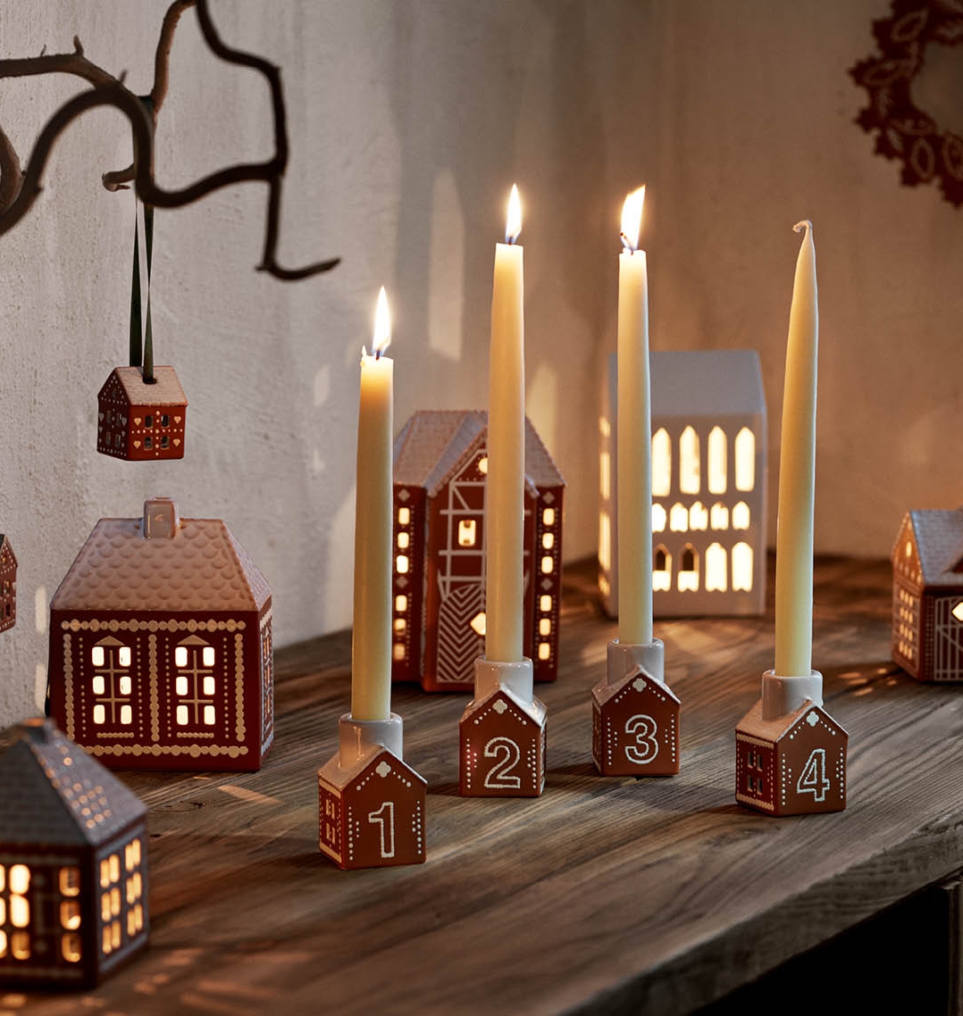 Tända adventsljus i små ljusstakar som ser ut som pepparkakshus