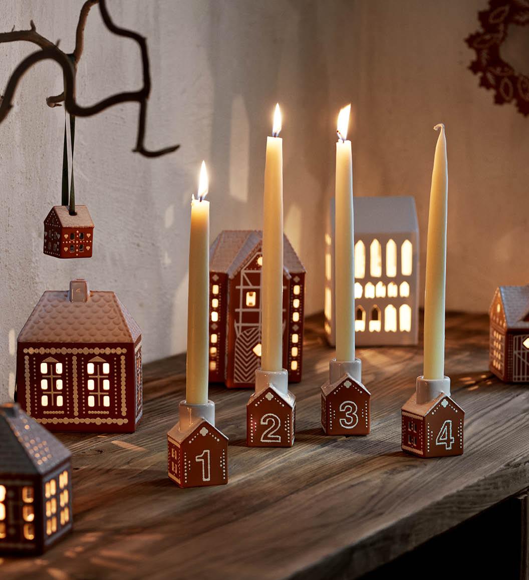 Tända adventsljus i små ljusstakar som ser ut som pepparkakshus