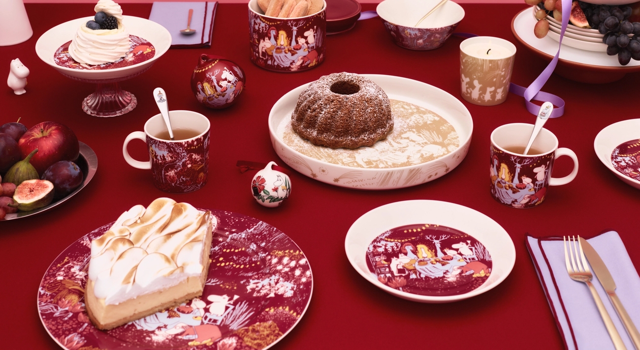 Ett festligt bord dukad med vinröd duk och Muminporslin i färgerna vinrött, gult och lila