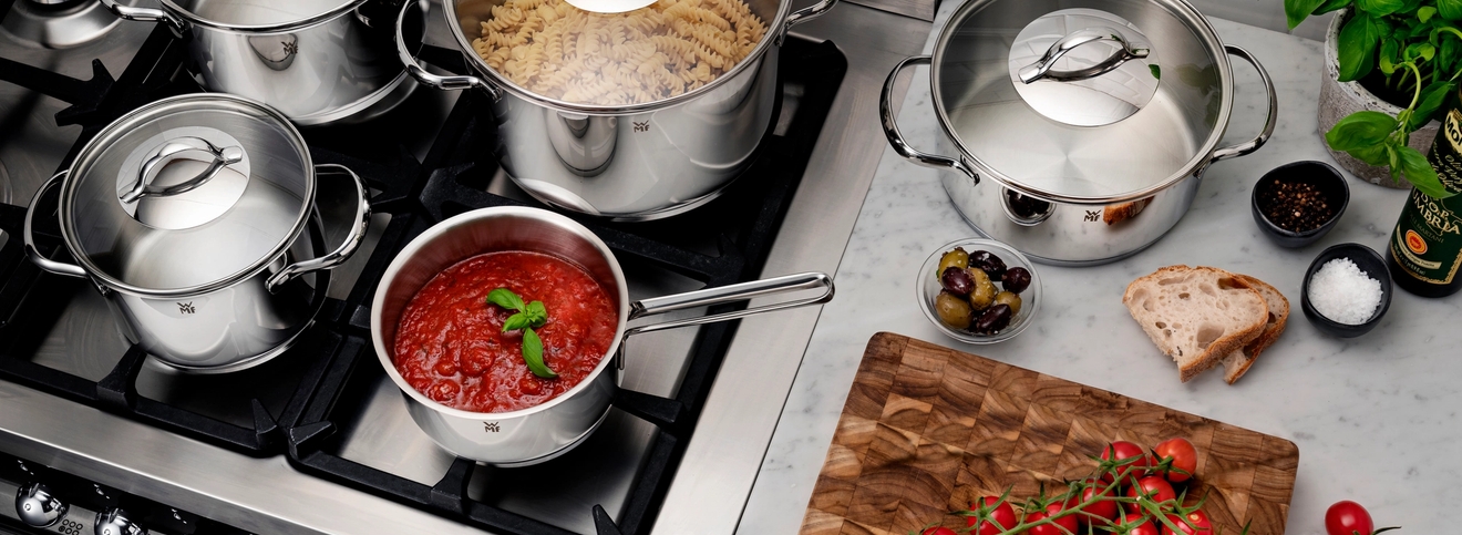 Erikokoiset WMF kattilat liedellä joissa lasikannet