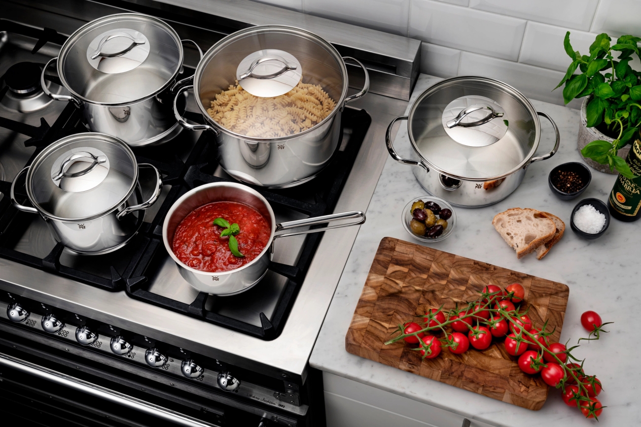 Erikokoiset WMF kattilat liedellä joissa lasikannet