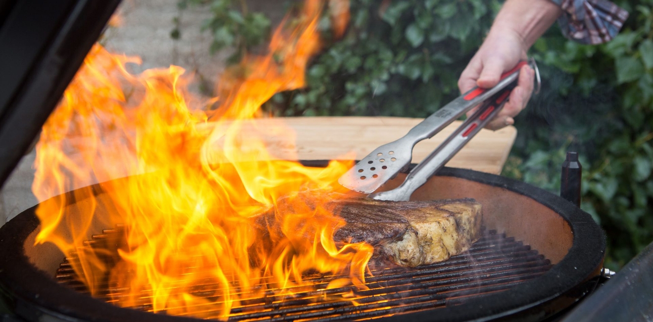 Grillredskaper, grilltang som skal snu kjøtt i en påtent grill