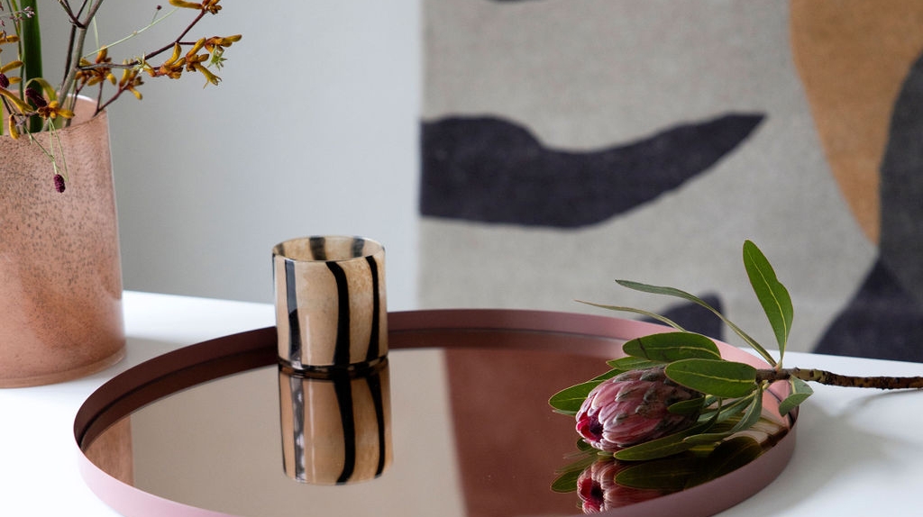 En brunrandig ljuslykta från Byon som står på en mörkröd bricka