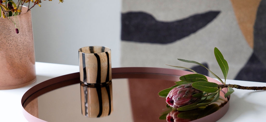 En brunrandig ljuslykta från Byon som står på en mörkröd bricka