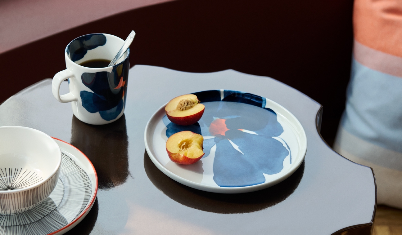 Marimekko mugg och tallrik i serien Valssi med blå blommönster på ett blankt bord