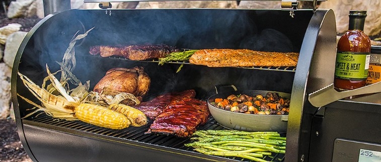 Pelletsgrill fylld med grillade majskolvar, revben, kyckling och sparris