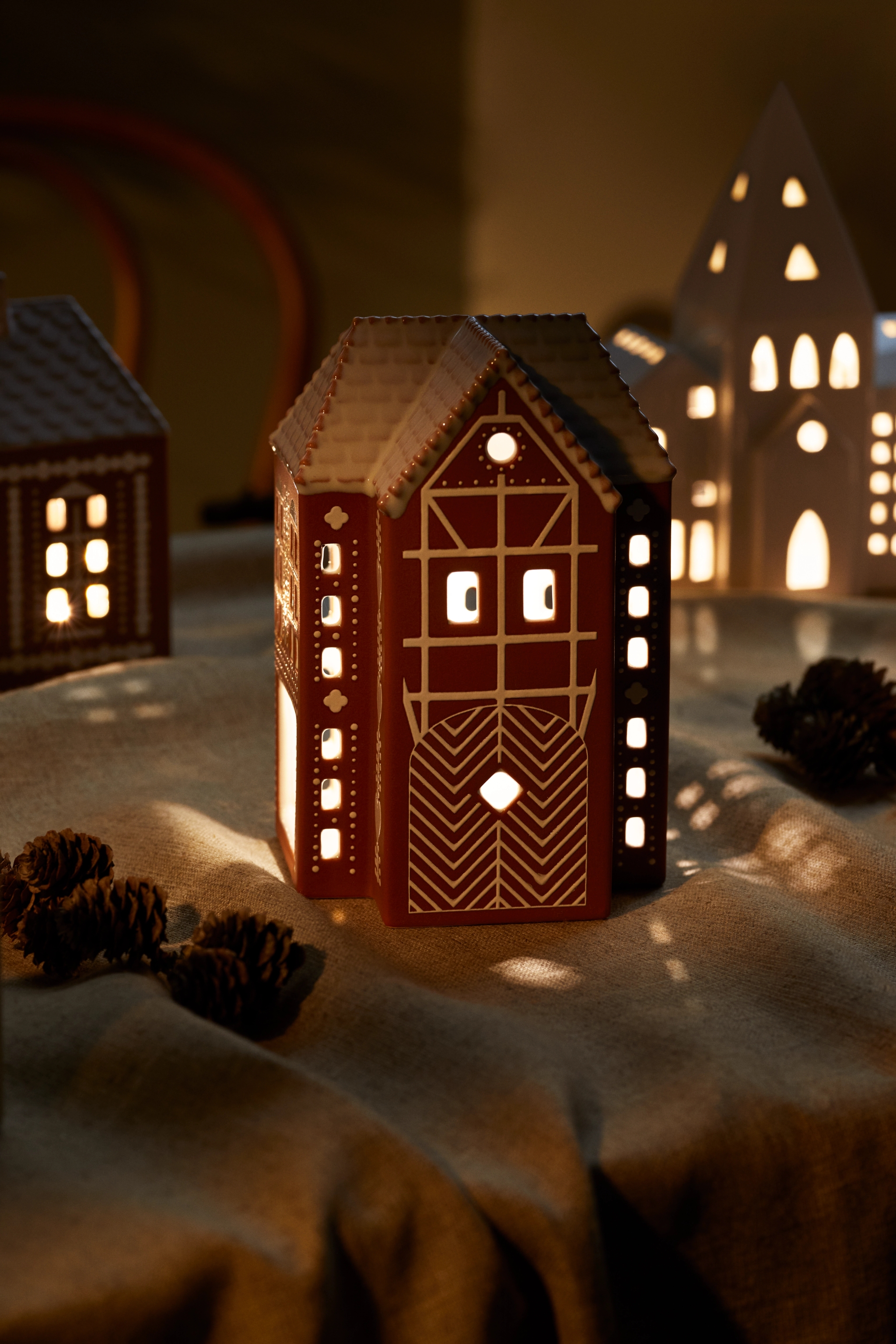 En ljuslykta som ser ut som ett pepparkakshus är tänd på ett bord