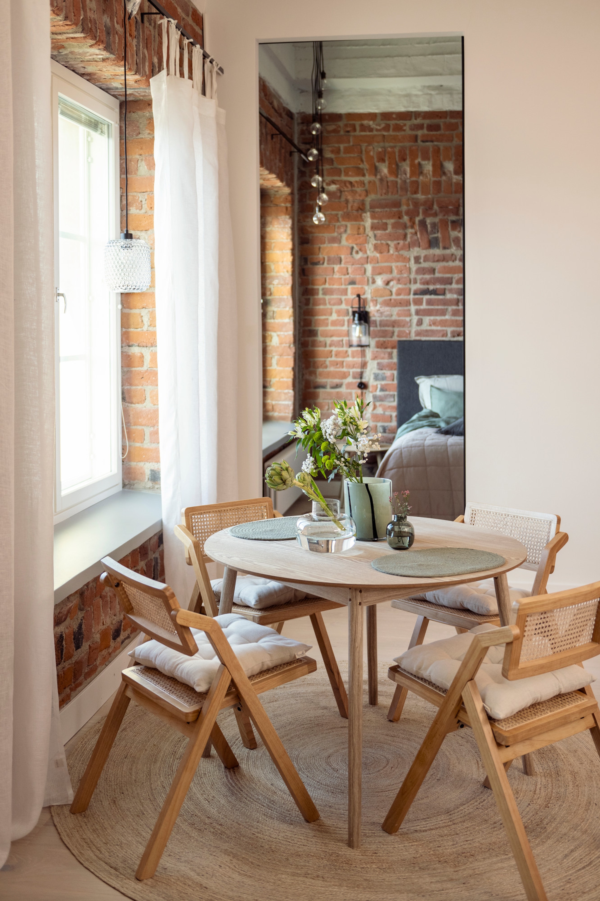 Matplats med runt bord med ljusa trästolar i ett hus med tegelväggar