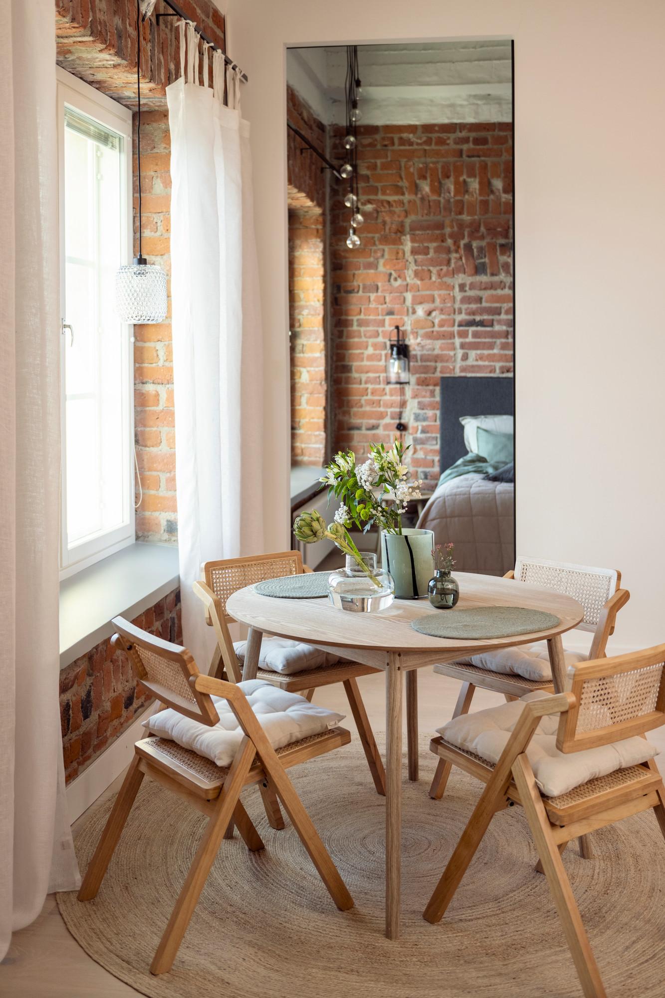 Matplats med runt bord med ljusa trästolar i ett hus med tegelväggar