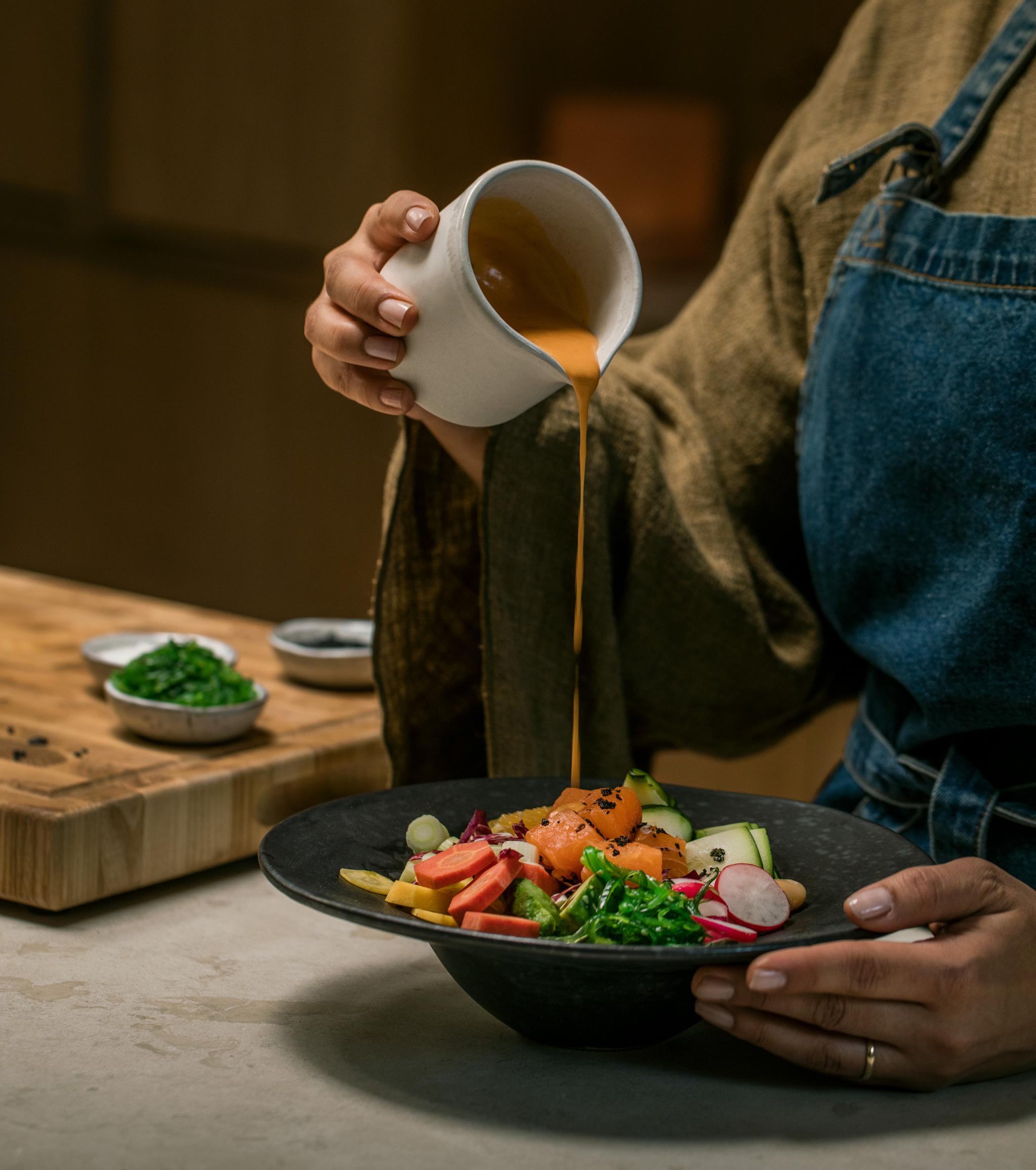 häller upp sås över tallrik med mat