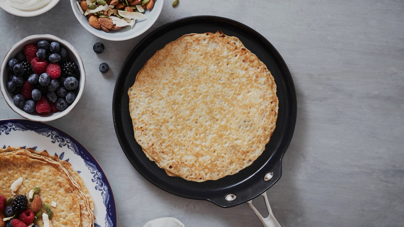 Pannkakspannor & Plättlagg med gräddad pannkaka med bär och nötter vid sidan 