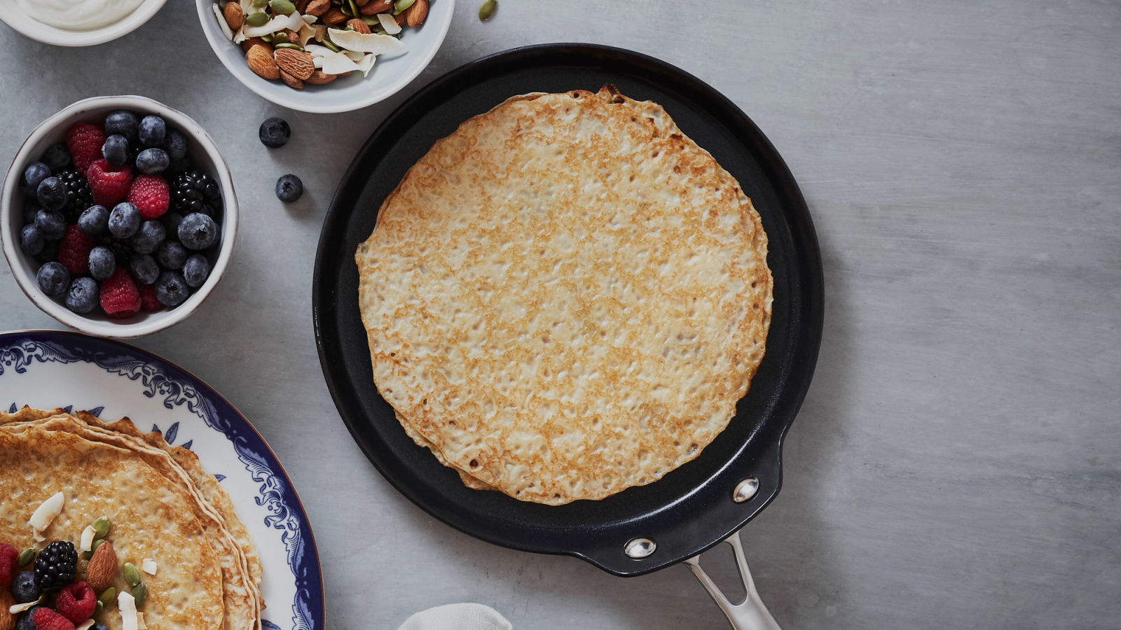 Pannkakspannor & Plättlagg med gräddad pannkaka med bär och nötter vid sidan