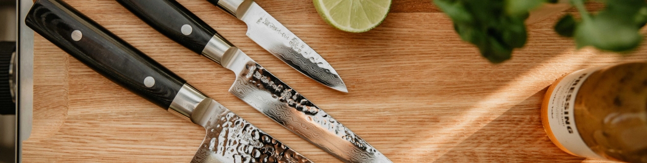 veitsisetit kolme erikokoista veistä puisella leikkuulaudalla