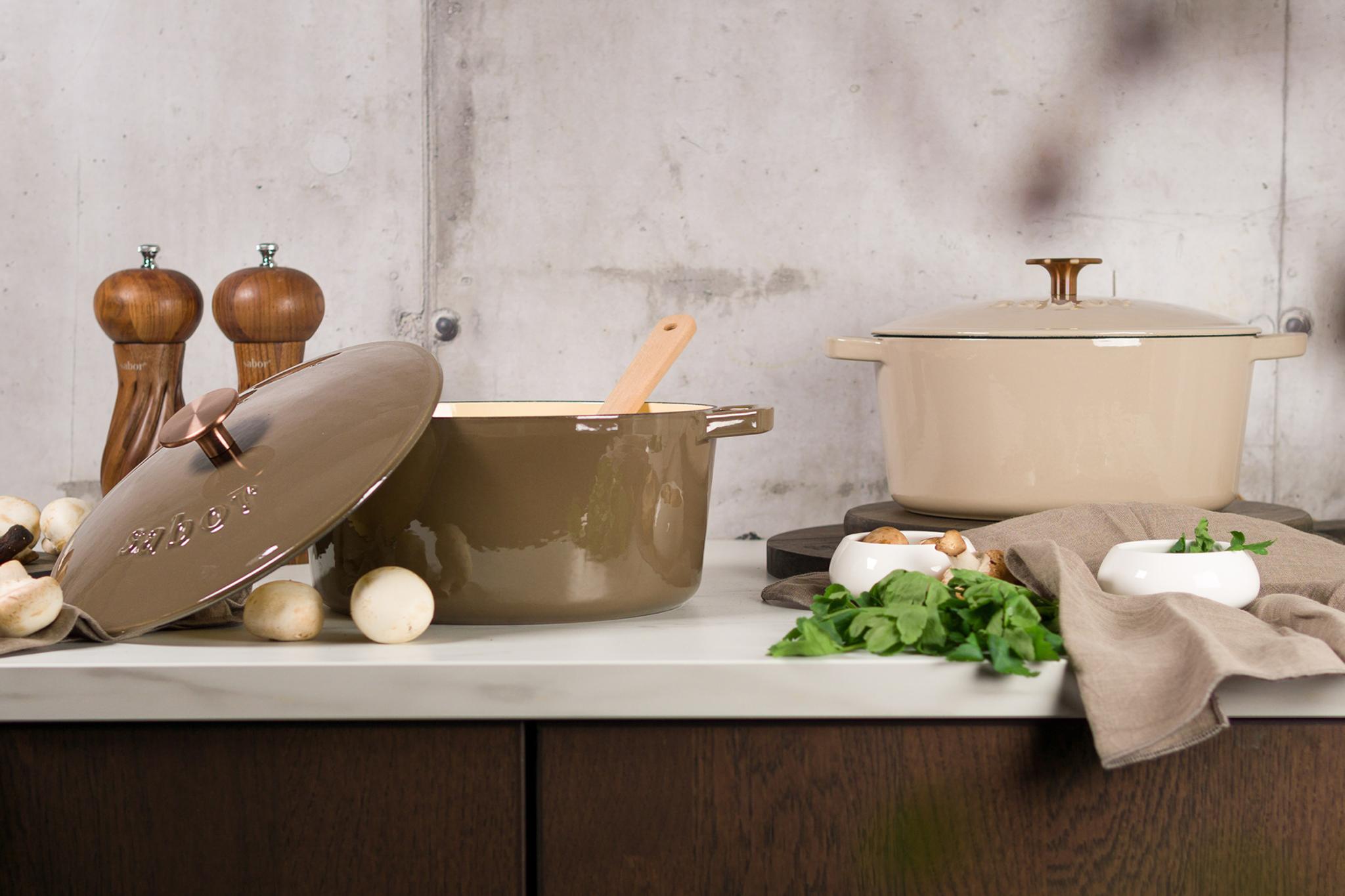 Sabor gjutjärnsgrytor i brunt och beige med svamp, örter och kvarnar på en köksbänk.