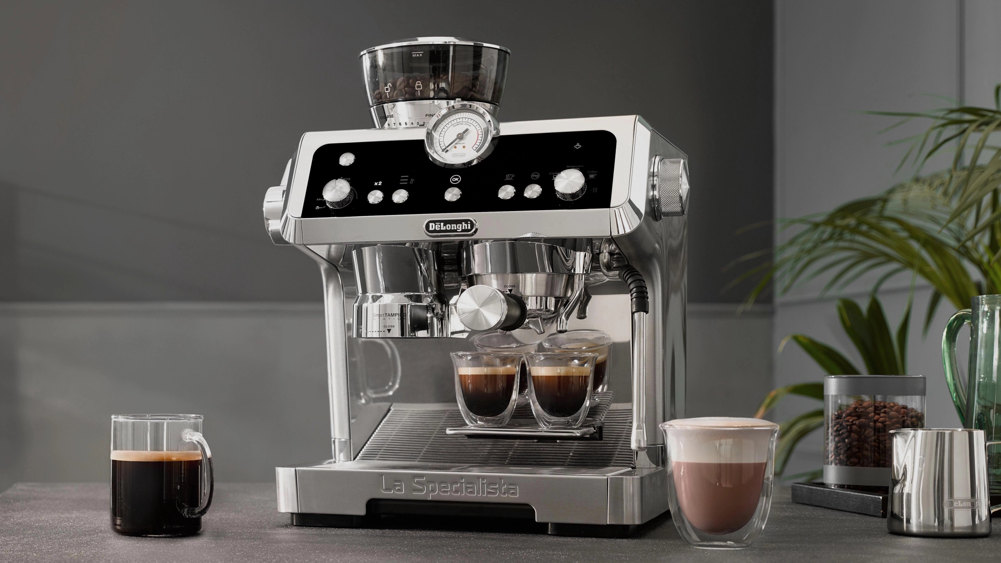 De’Longhi La Specialista espressokone keittiötasolla, vierellään kaksi espressoa, yksi kahvi ja latte.