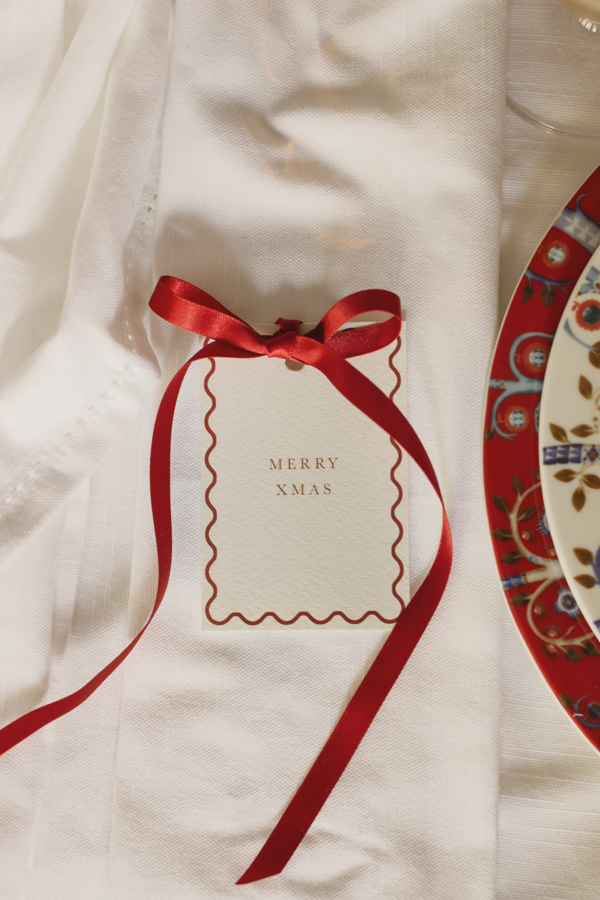 a card that says merry xmas is tied with a red ribbon
