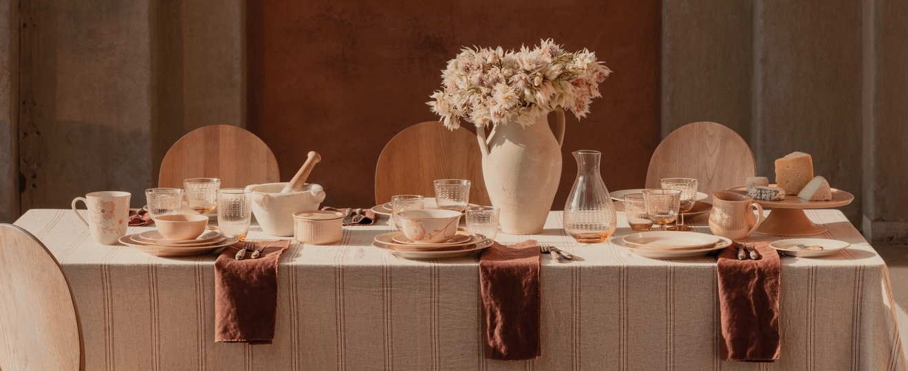 Dukat bord med ljust terrakottafärgat porslin med mönster av fåglar och blommor