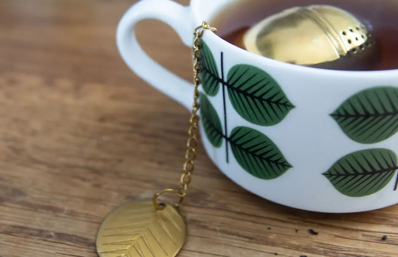 Berså kopp från Stig Lindberg med te i och en mässings tekula