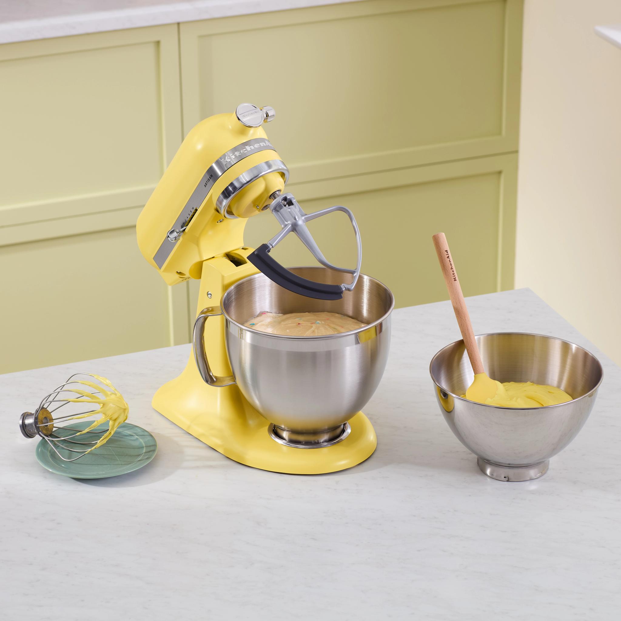 En gul KitchenAid köksmaskin som står på en köksbänk  i ljus marmor