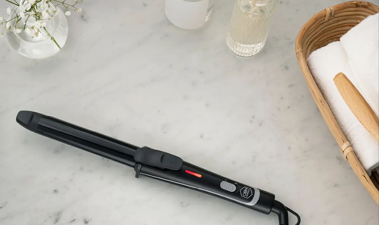 a hair curler is sitting on a marble counter next to a basket of towels .