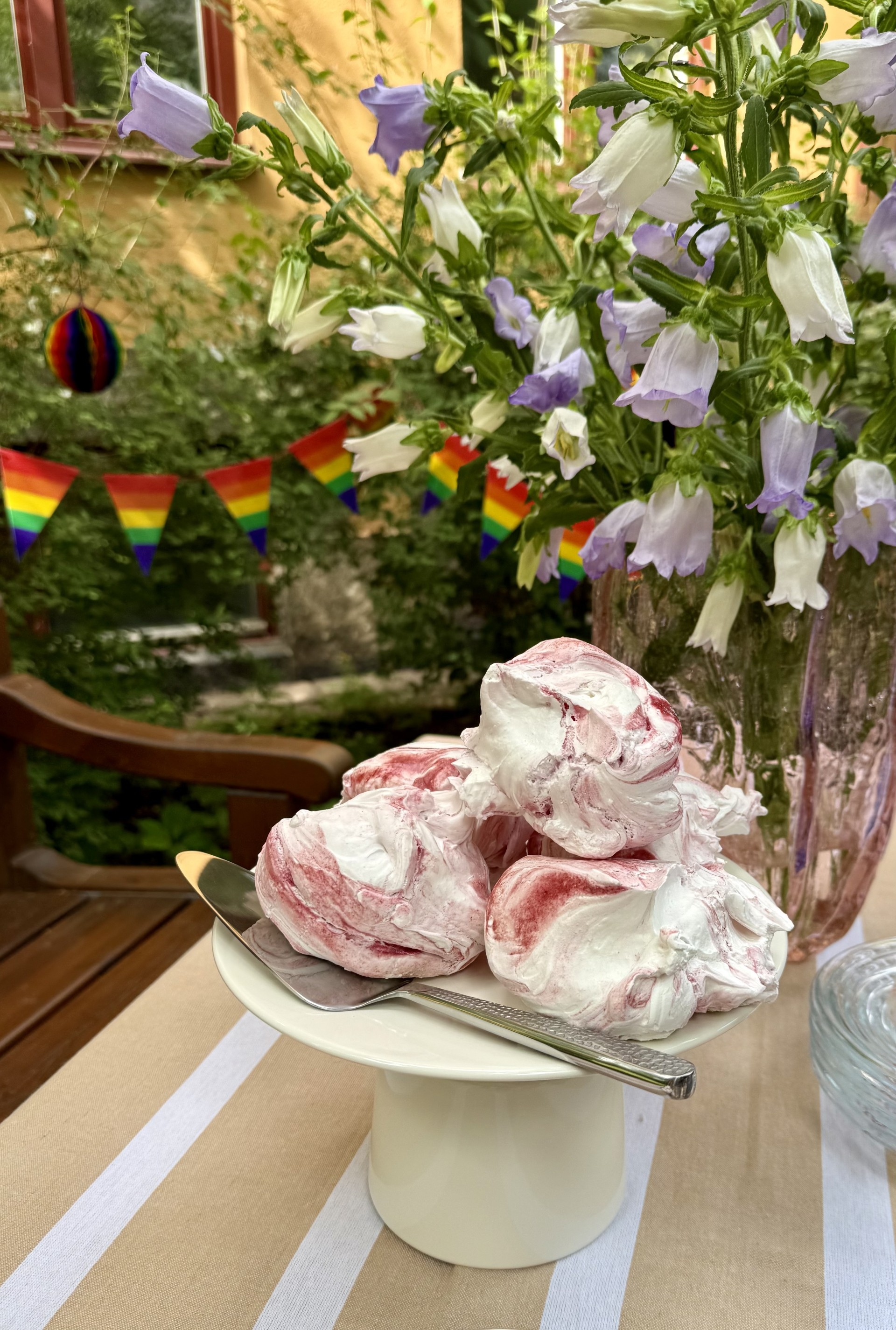 a plate of food with a spoon on a table with flowers in the background