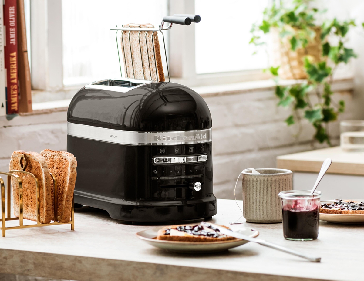 Tyylikäs musta KitchenAid-leivänpaahdin modernilla keittiön tasolla paahtoleivän, hillon ja teen kanssa.