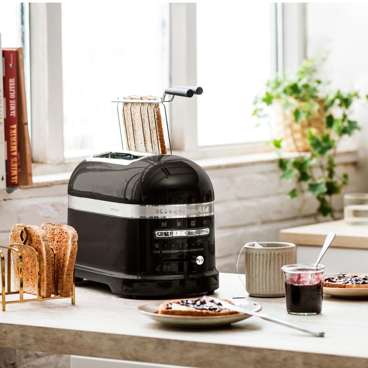 Tyylikäs musta KitchenAid-leivänpaahdin modernissa keittiössä paahtoleipien ja aamiaistarvikkeiden kanssa.