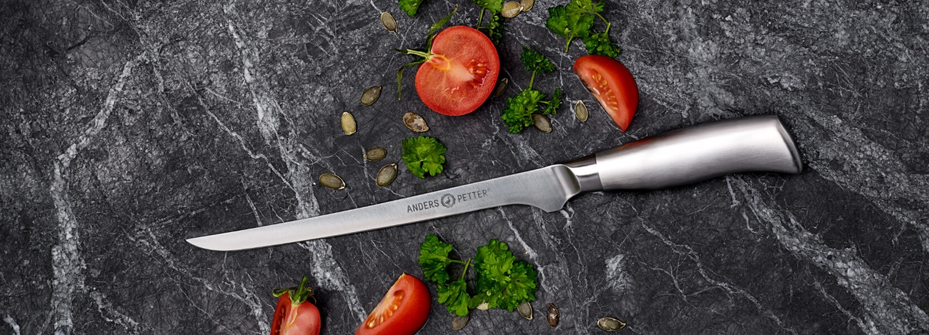 Filékniv Anders Petter på marmorbord med skurna tomater och persilja 
