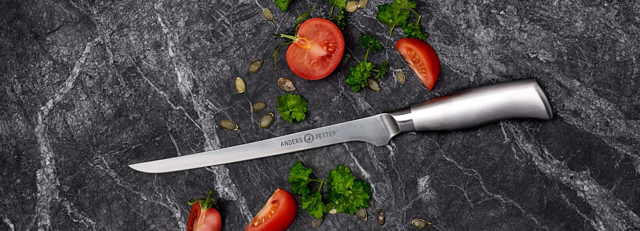 Filékniv Anders Petter på marmorbord med skurna tomater och persilja 