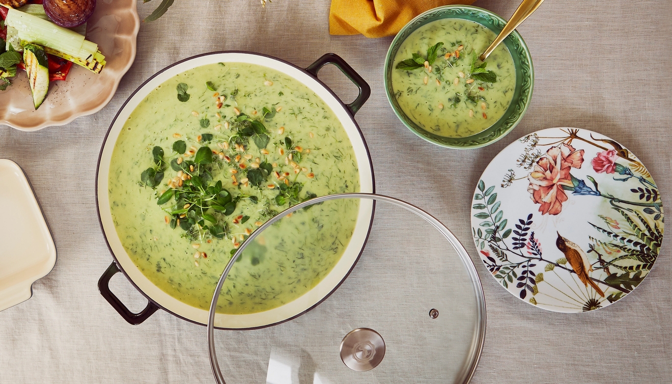 Ovanifrånvy av ett matbord med en stor gryta med grön soppa, grillade grönsaker och rostad broccoli.