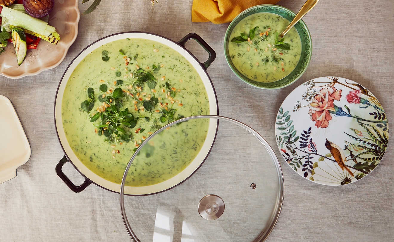 Ylhäältä päin kuvattu ruokapöytä, jossa on suuri kattilallinen viherkeittoa, grillattuja kasviksia ja paahdettua parsakaalia.