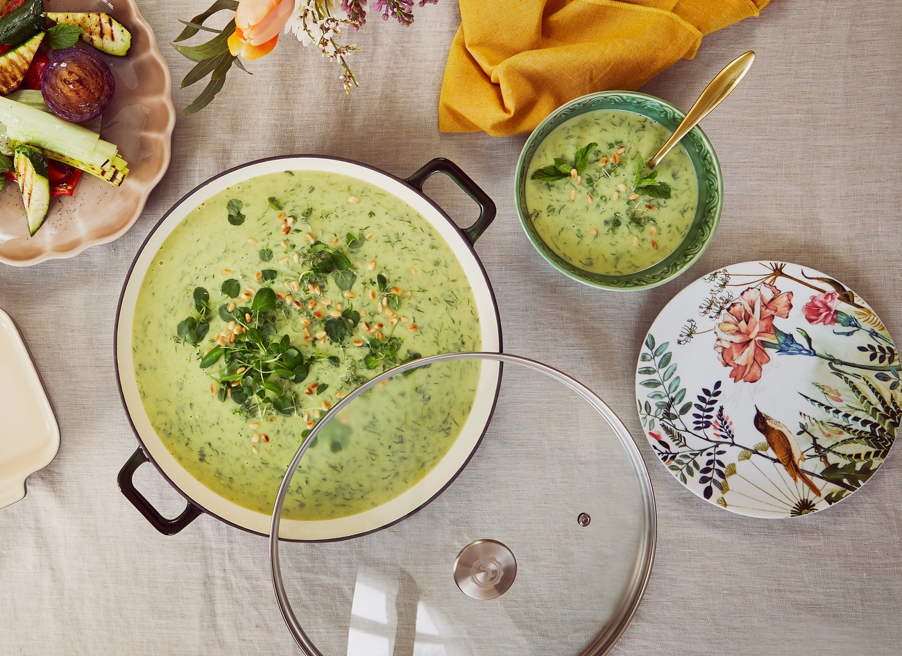 Ovanifrånvy av ett matbord med en stor gryta med grön soppa, grillade grönsaker och rostad broccoli.
