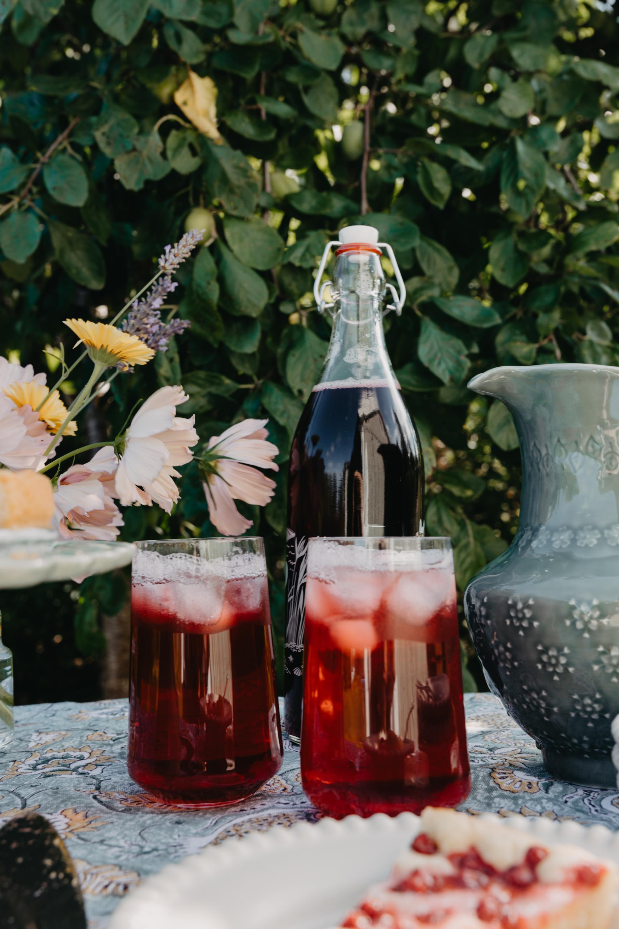 Hemmagjord saft i glas som står på ett bord ute i trädgården