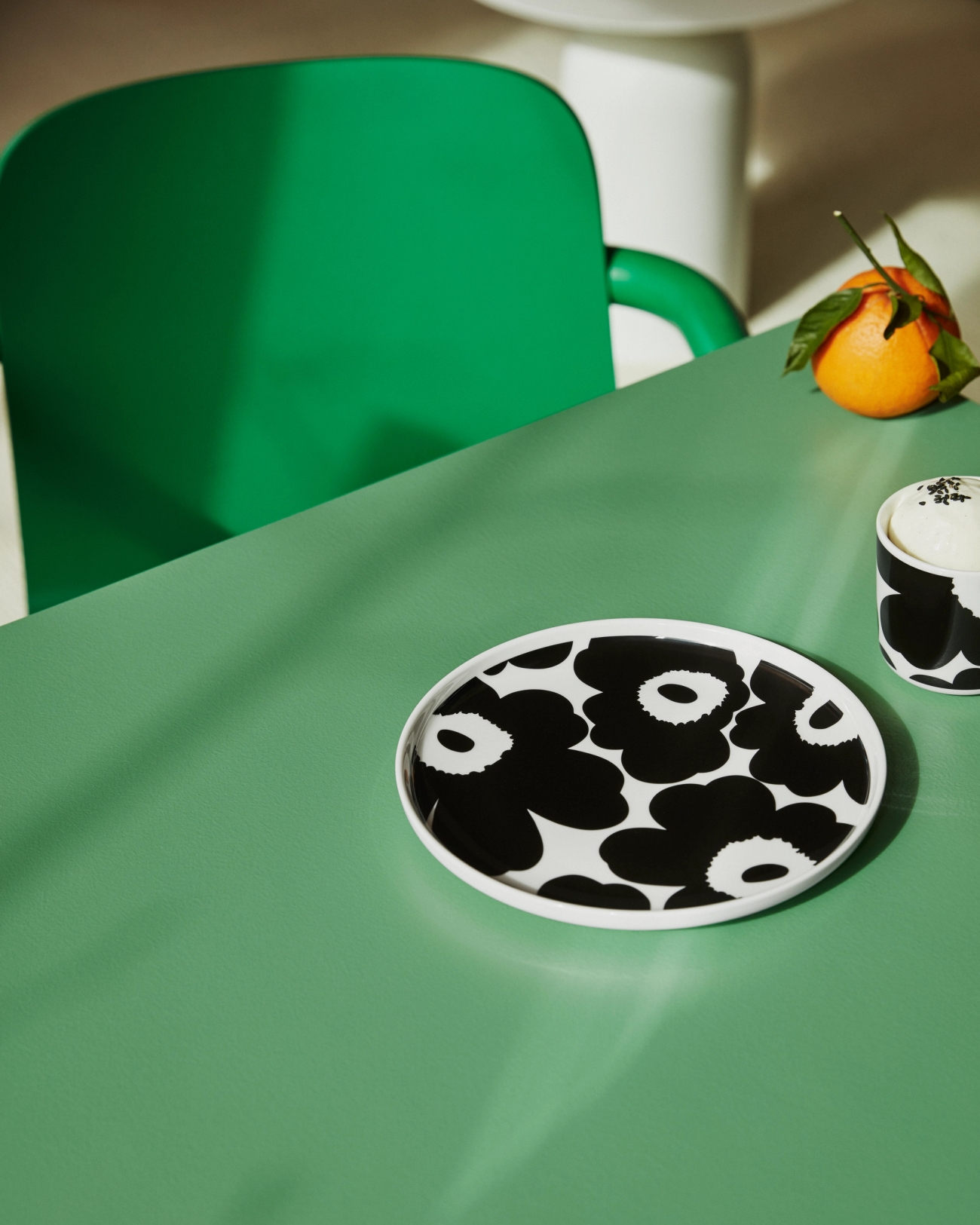 Marimekko tallrik från serien Unikko i svart och vitt på grönt bord
