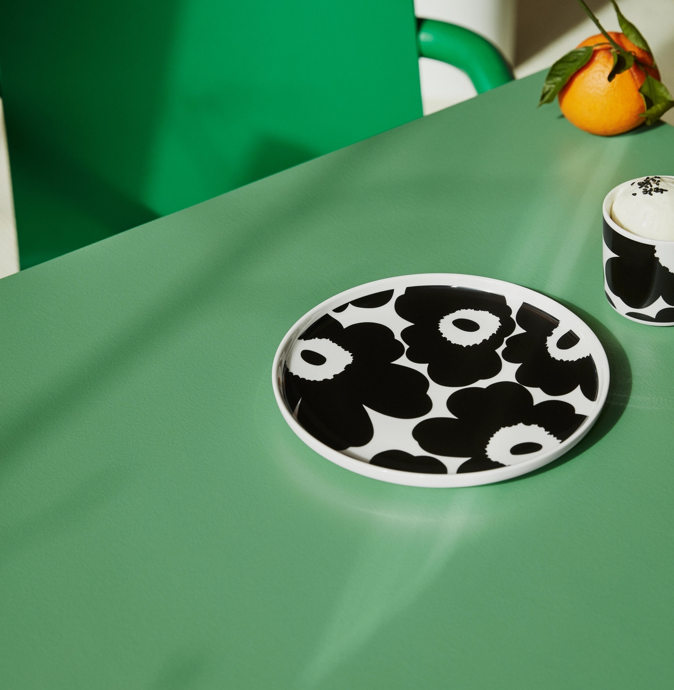 Marimekko tallrik från serien Unikko i svart och vitt på grönt bord