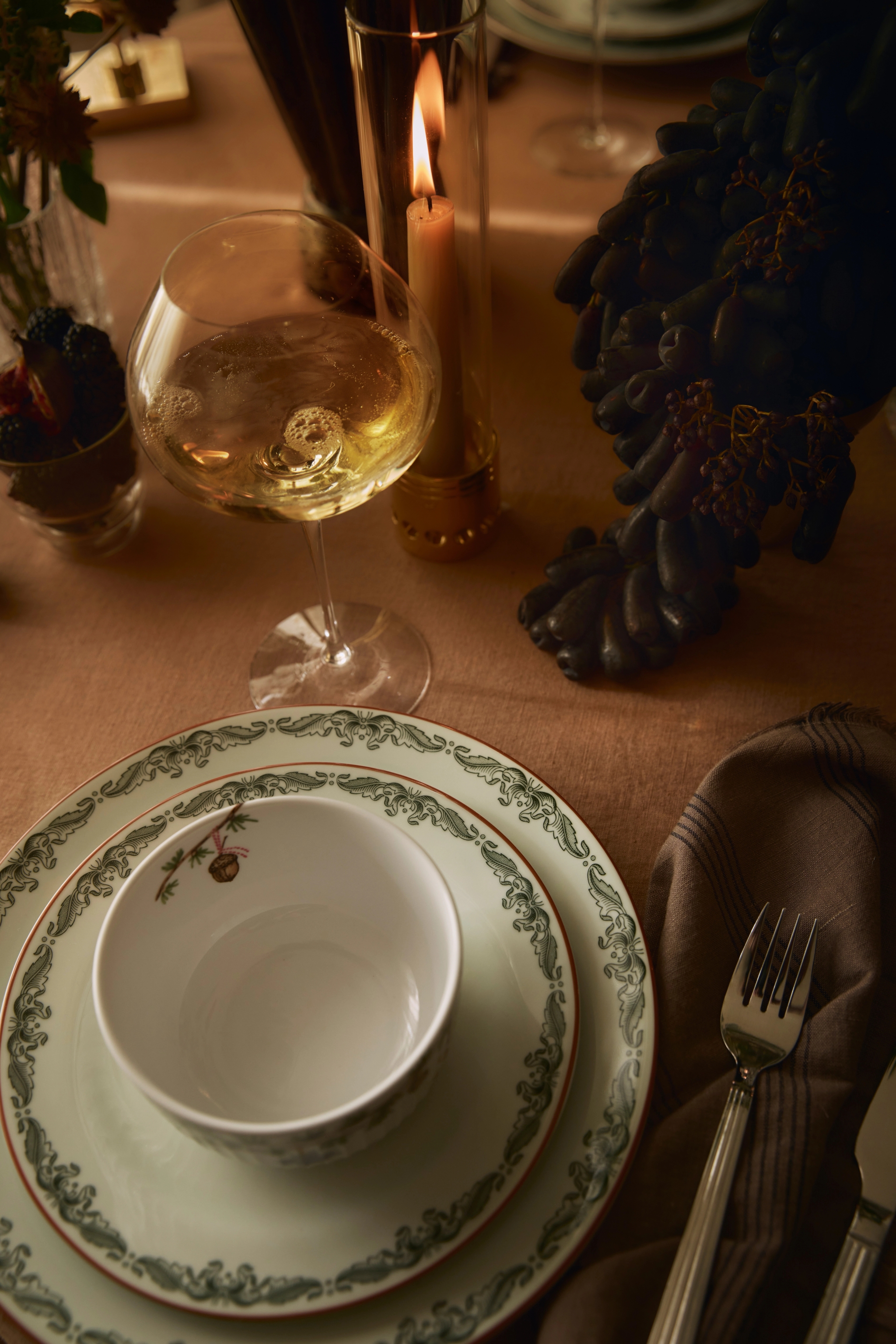 a table setting with plates a bowl and a glass of wine