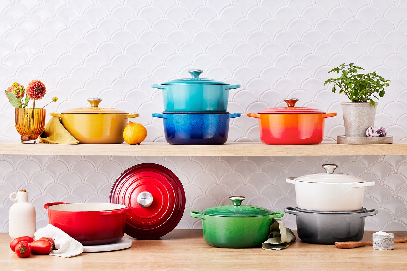Le Creuset støpejernsgryter i alle regnbuens farger på en hylle på et kjøkken