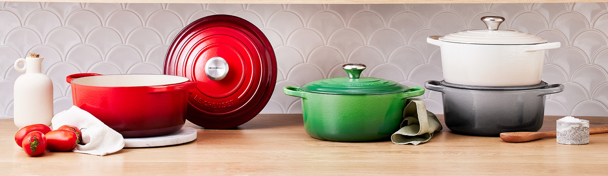 Le Creuset støpejernsgryter i alle regnbuens farger på en hylle på et kjøkken
