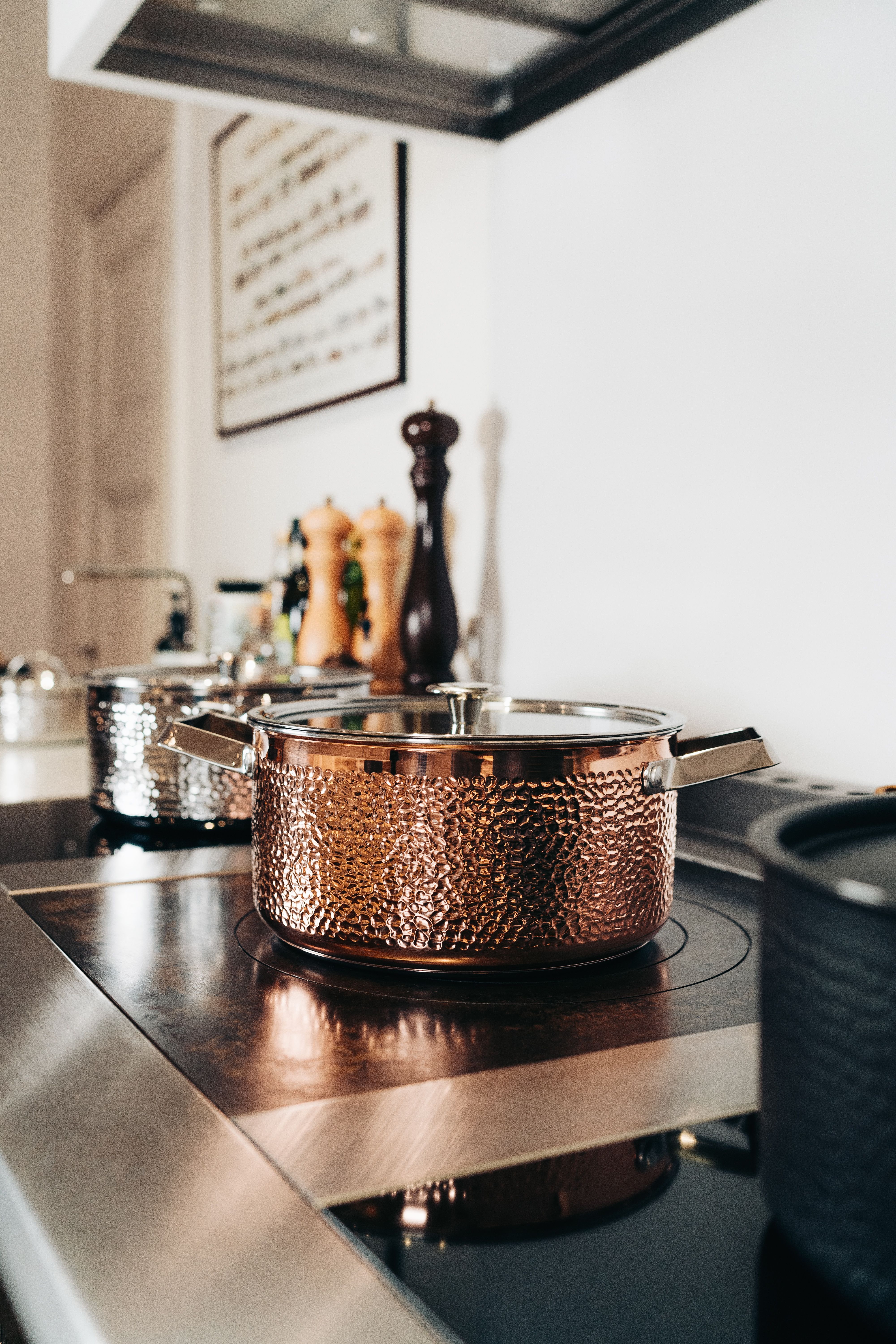 Hamrad koppargryta på en spishäll med andra köksredskap och kvarnar.