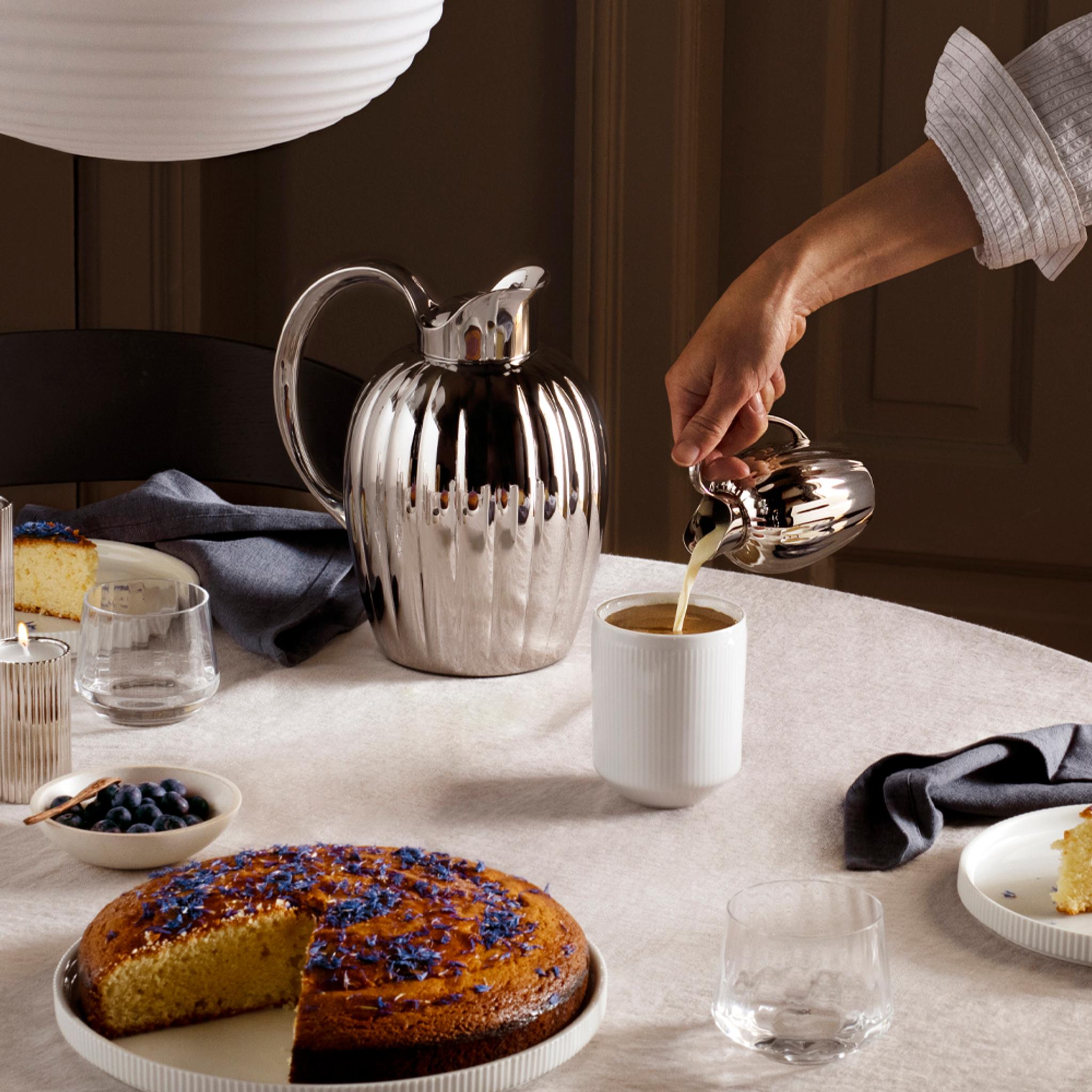 En termoskanna i stål från Georg Jensen står på ett bord dukat för fika