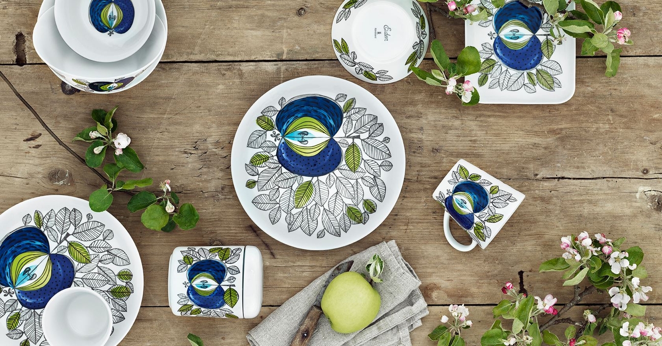 Eden tallrik och kopp på bord med äpple och blommor
