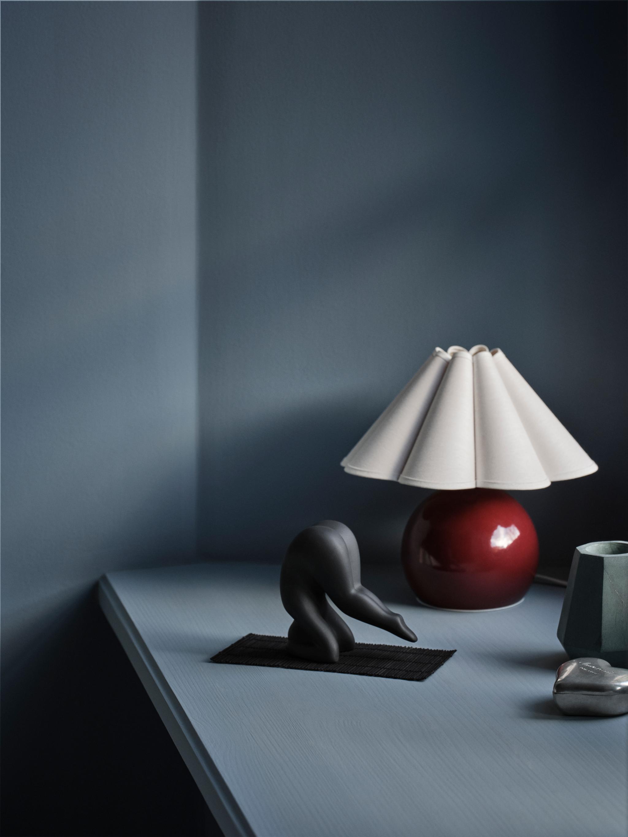 Lisa Larson Yoga figur i svart mot en mörkblå bakgrund