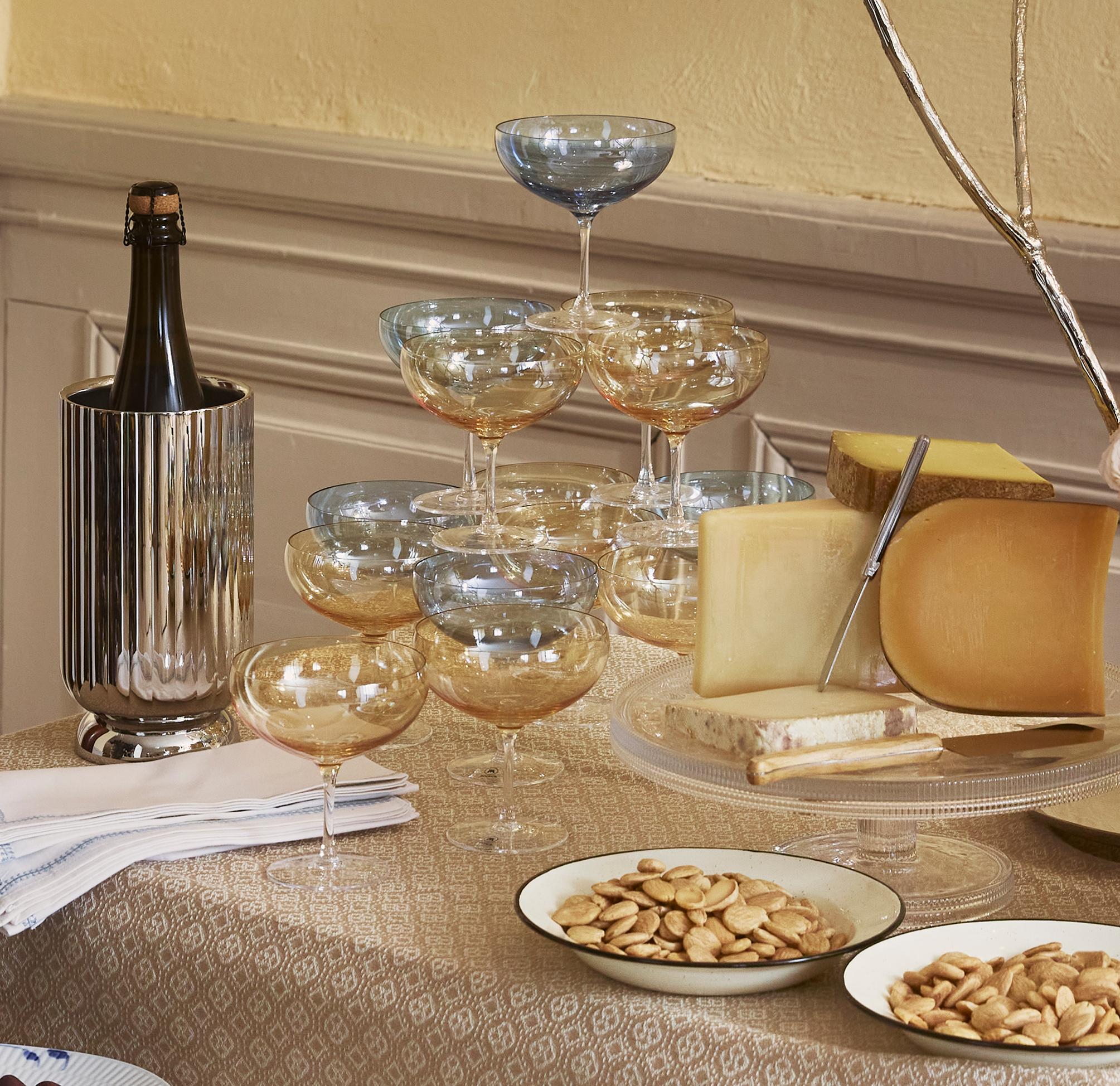 Elegant festbord med brød, ost, druer, vin og tente lys i et klassisk, varmt opplyst rom.