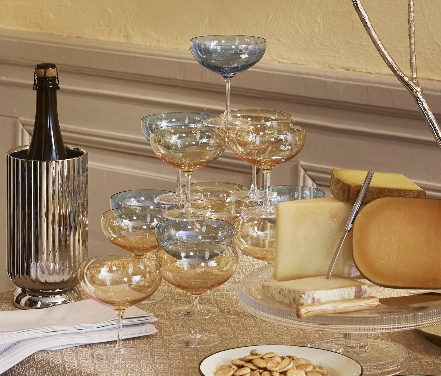 Elegant festbord med ost, brød, druer, vin og tente lys i et klassisk, varmt innredet rom.