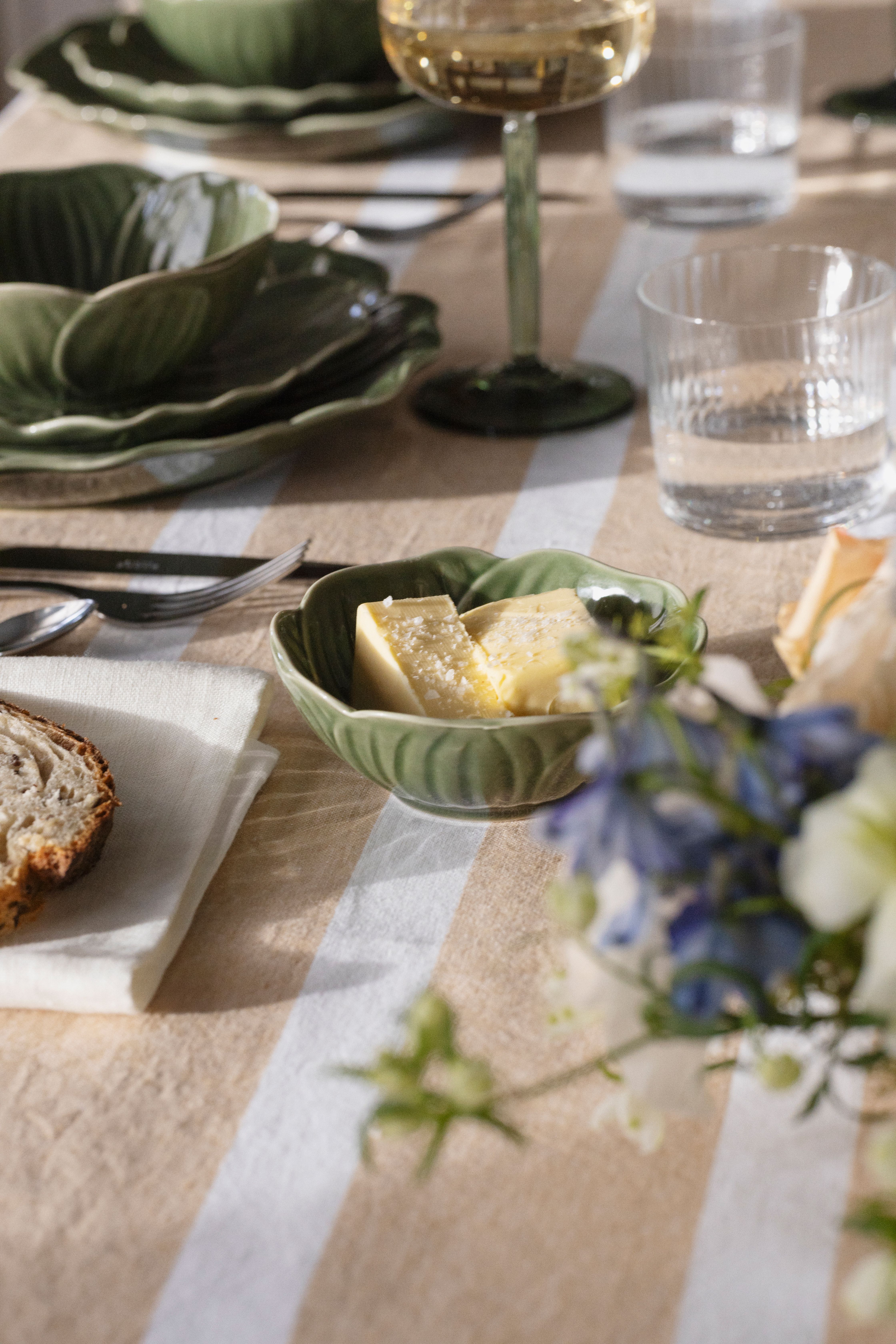 Närbild på dukning med Stiernholm Flora i grönt på randig duk i puderrosa