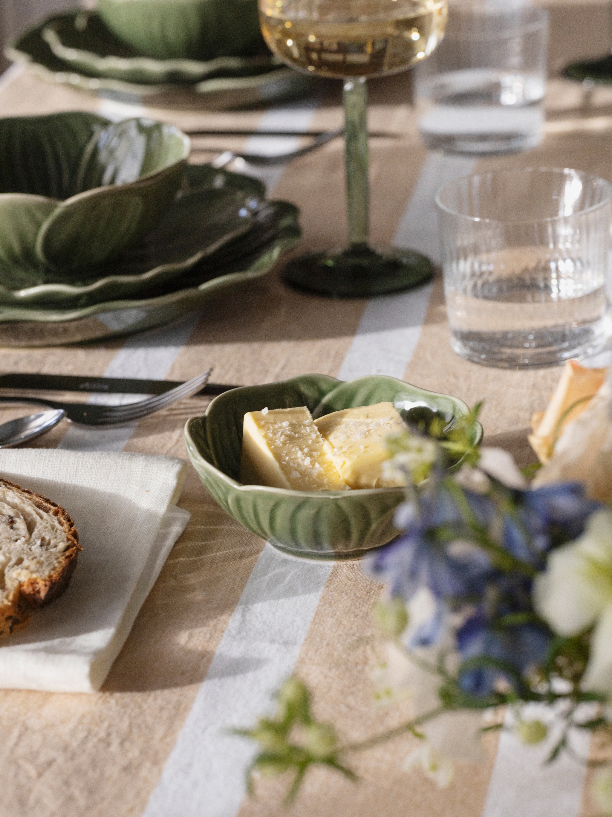 Närbild på dukning med Stiernholm Flora i grönt på randig duk i puderrosa