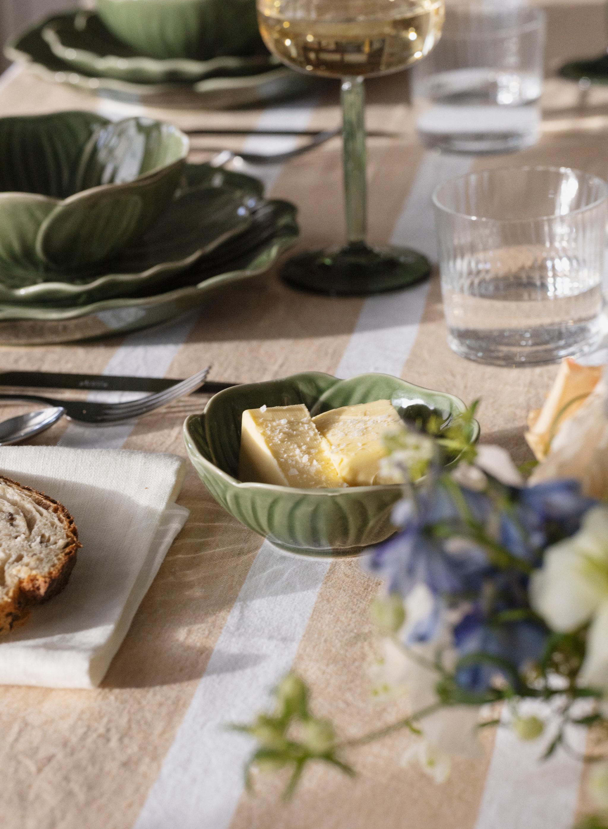 Närbild på dukning med Stiernholm Flora i grönt på randig duk i puderrosa
