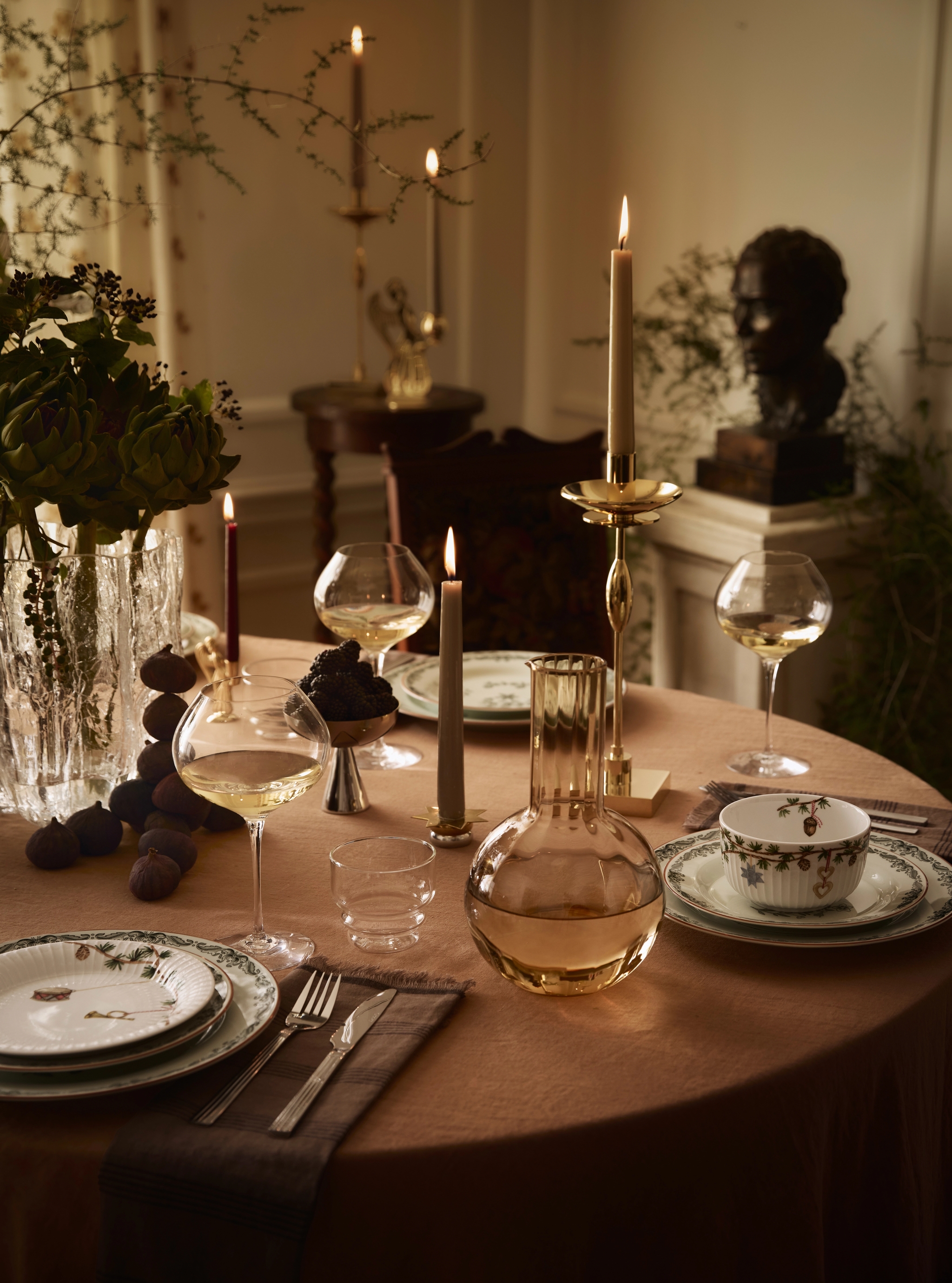 ett bord dukat med tallrikar, ljus och en vas med blommor