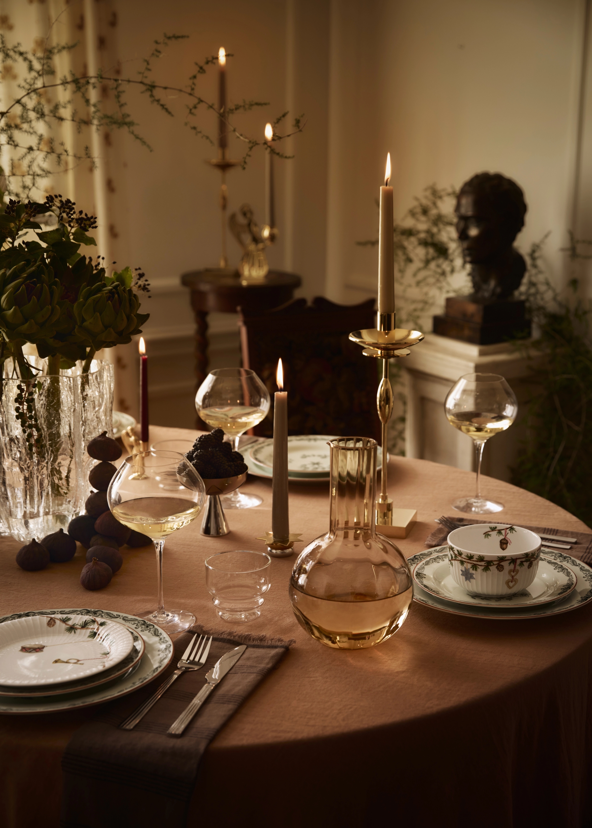 a table set with plates candles and a vase of flowers